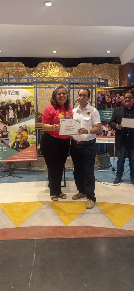 man wearing a black jacket, white shirt, blue jeans, and brown boots, playing a white electric guitar while sitting on an amp